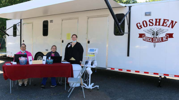 From left, Dionne Robinson, MA, site leader at the Hamlet, Rockingham and Albemarle Goshen locations, Tara Clark, MA, Goshen medical assistant, and Nurse Practitioner Sheila Brown, DNP, AGNP-C, pose in front of the Goshen Medical Center mobile unit in Albemarle during a recent health fair at Monarch.